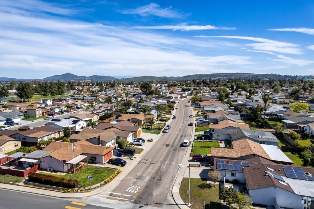 Coastal neighborhood with homes, palm trees, and ocean views along a scenic residential street near the shoreline.