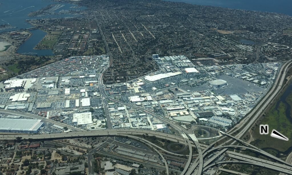 Aerial view of San Diego's Midway District showing highways, commercial buildings, parking lots, and coastal waterways.